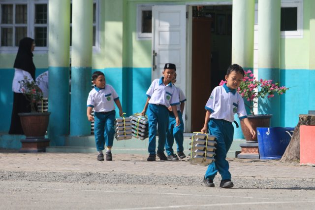 Sejumlah siswa membawa ompreng Makan Bergizi Gratis (MBG) di kompleks Madrasah Ibtidayyah Negeri (MIN) 11 Aceh Barat Desa Kuta Padang, Johan Pahlawan, Aceh Barat, Aceh, Senin (21/9/2026).